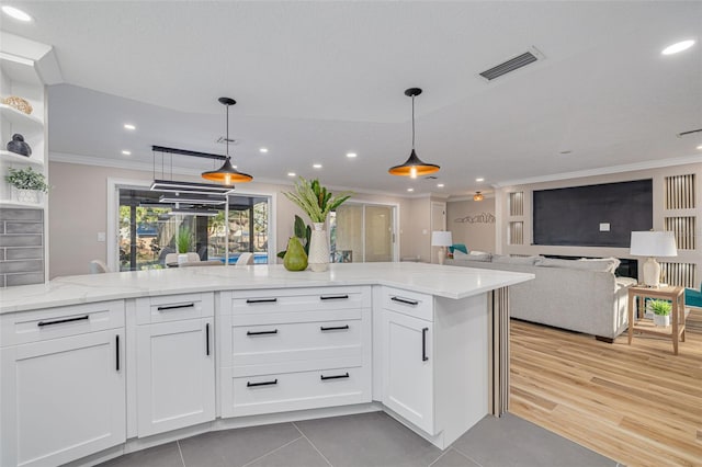 kitchen featuring white cabinetry, ornamental molding, light stone counters, and hanging light fixtures