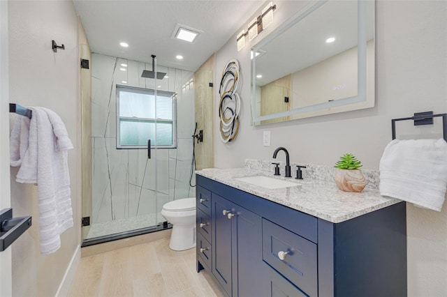 bathroom with vanity, toilet, a shower with door, and hardwood / wood-style floors