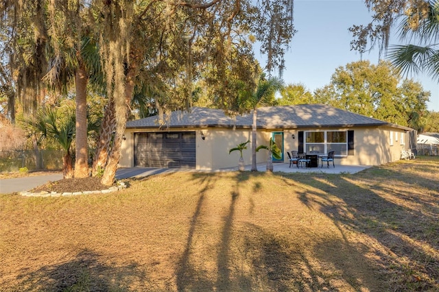 view of front facade with a garage, a front lawn, and a patio area