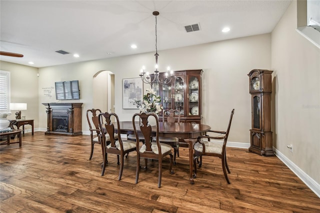 8144 Sequester Loop, Land O Lakes, FL 34637 - dining space featuring a chandelier, arched walkways, dark wood finished floors, a fireplace, and recessed lighting