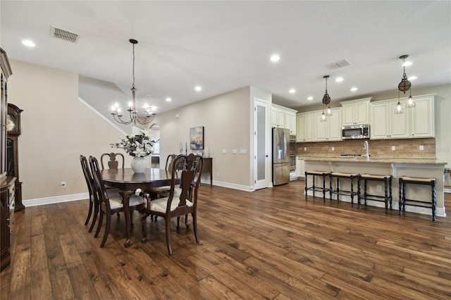 dining area with sink, dark wood-type flooring, and a chandelier