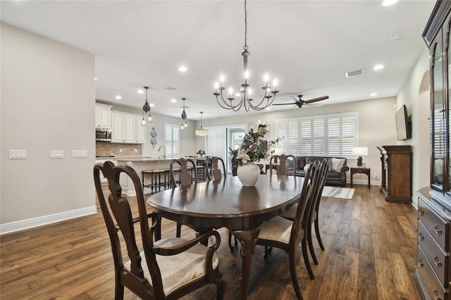 dining area with ceiling fan with notable chandelier, dark wood-type flooring, and sink