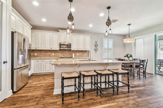 kitchen featuring sink, an island with sink, stainless steel appliances, and light wood-type flooring