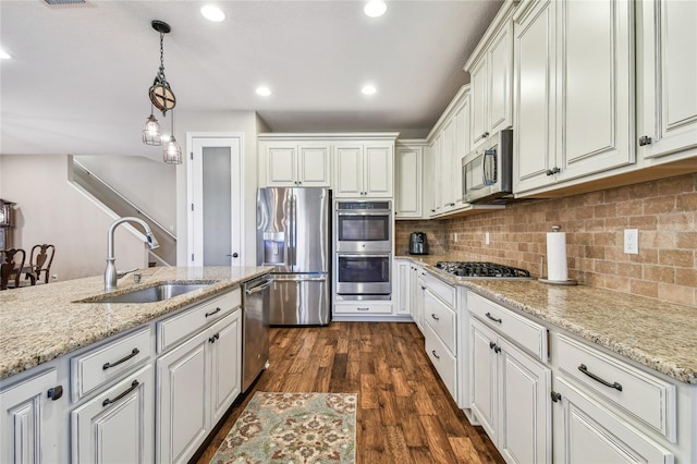 kitchen featuring light stone countertops, sink, dark wood-type flooring, stainless steel appliances, and decorative light fixtures