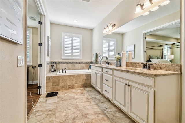 bathroom with a relaxing tiled tub and vanity