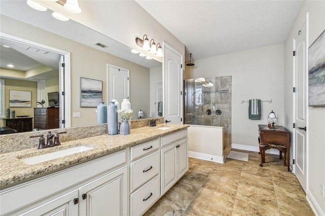 bathroom with a tile shower and vanity