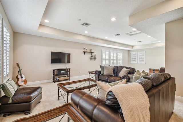 living room featuring light colored carpet, a textured ceiling, and a tray ceiling