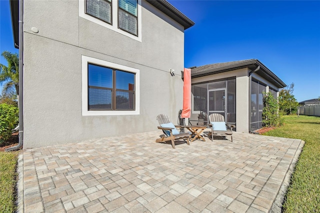 back of property with a yard, a patio area, and a sunroom