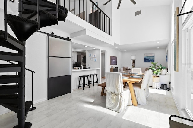 dining area with a barn door, a high ceiling, and light wood-type flooring