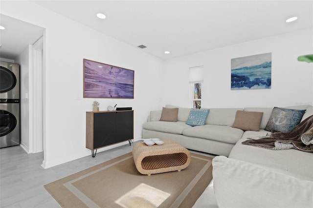 living room featuring light hardwood / wood-style flooring and stacked washer / dryer