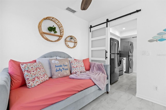 bedroom featuring black refrigerator, a barn door, and ceiling fan