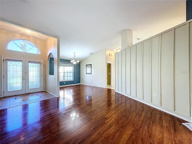 foyer with a chandelier, french doors, lofted ceiling, and dark wood-type flooring