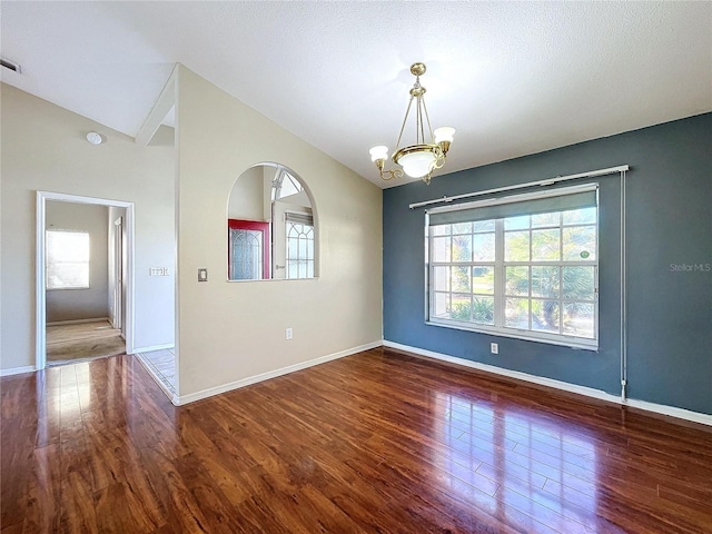 spare room with dark wood-type flooring and a notable chandelier