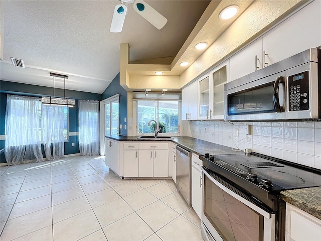 kitchen featuring tasteful backsplash, stainless steel appliances, vaulted ceiling, sink, and white cabinets