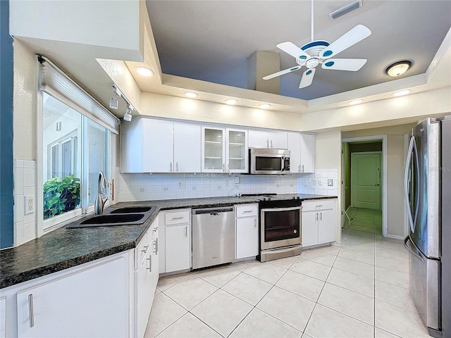 kitchen with stainless steel appliances, a raised ceiling, white cabinetry, and sink