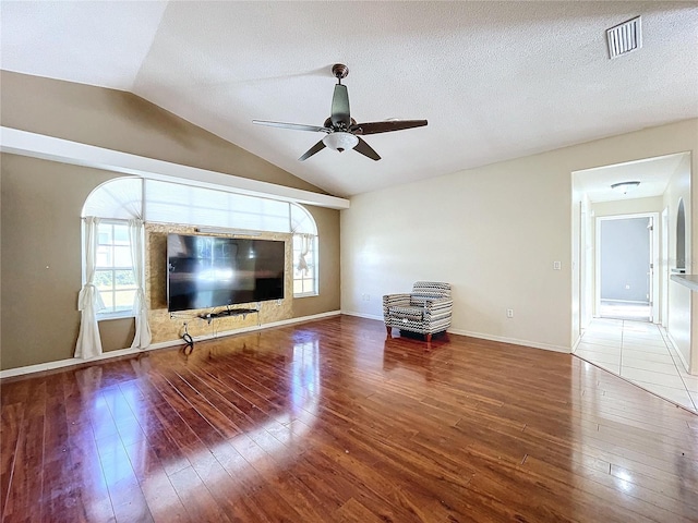 unfurnished living room featuring hardwood / wood-style floors, ceiling fan, a textured ceiling, and vaulted ceiling