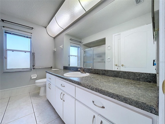 bathroom featuring tile patterned flooring, a textured ceiling, toilet, a shower with door, and vanity