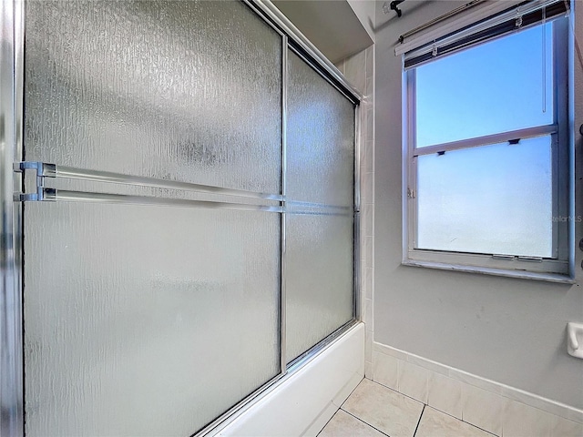 bathroom with tile patterned flooring, a wealth of natural light, and bath / shower combo with glass door