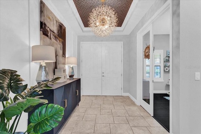 entryway with a raised ceiling, crown molding, and an inviting chandelier