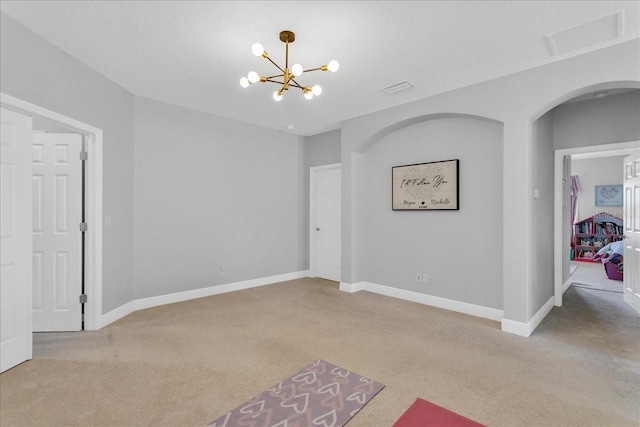 carpeted spare room with a notable chandelier