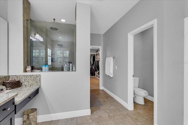 bathroom with tiled shower, vanity, and toilet