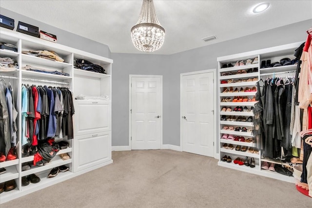 walk in closet featuring light colored carpet and a notable chandelier