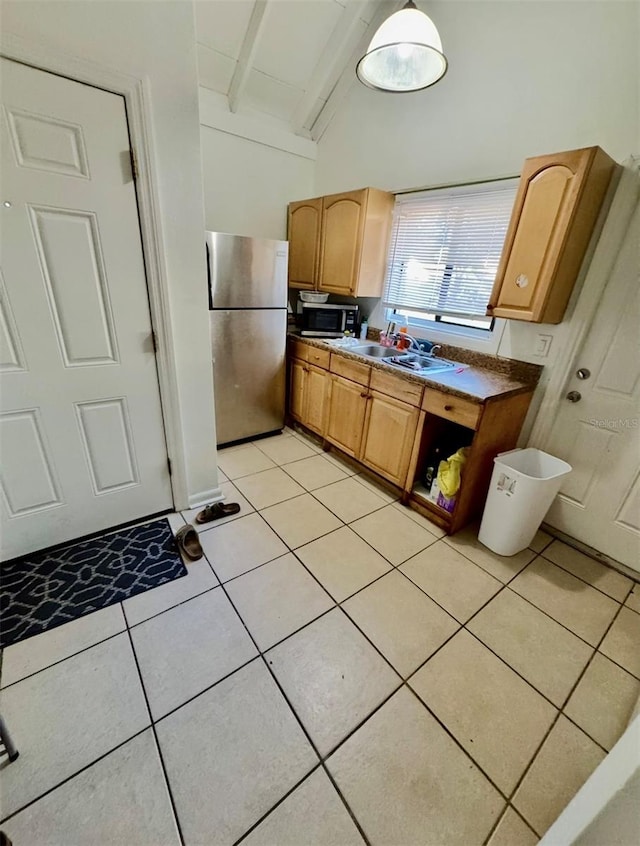 kitchen with light tile patterned floors, lofted ceiling with beams, stainless steel appliances, and sink