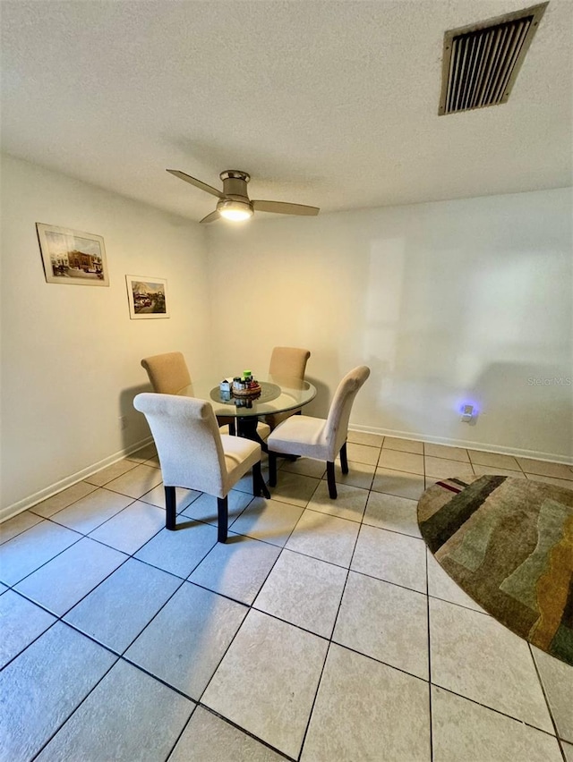 dining space with ceiling fan, light tile patterned flooring, and a textured ceiling