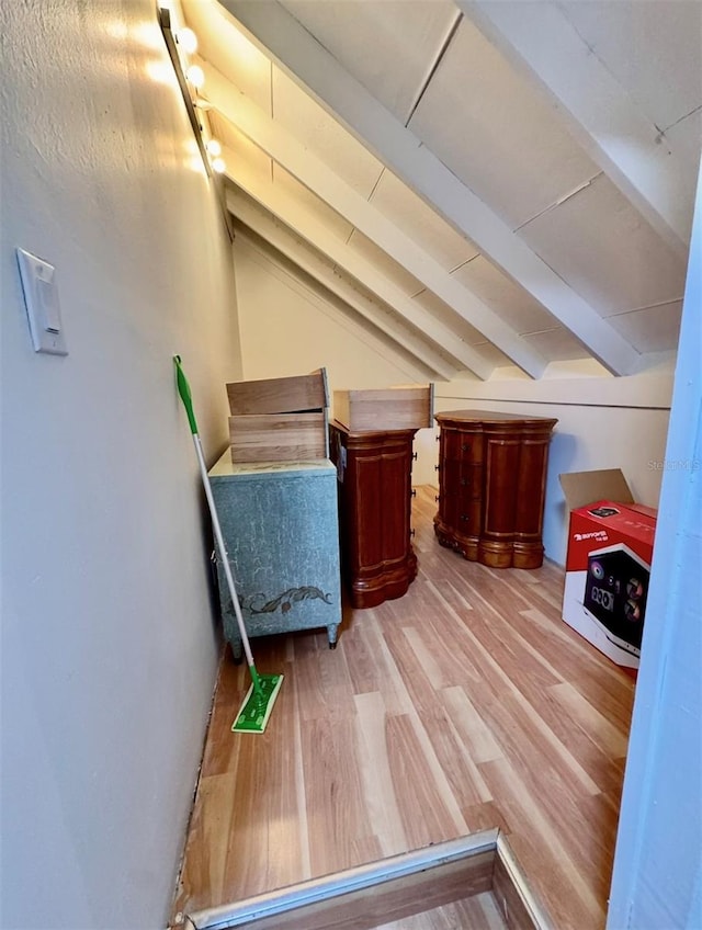 additional living space featuring lofted ceiling with beams and light hardwood / wood-style flooring