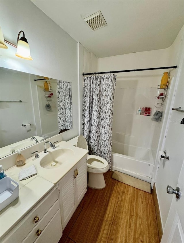 full bathroom featuring hardwood / wood-style floors, vanity, shower / tub combo, and toilet