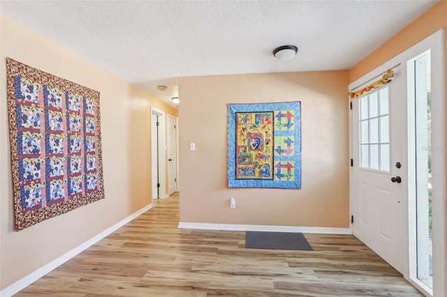 foyer entrance with a textured ceiling and light hardwood / wood-style flooring