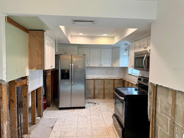 kitchen featuring a raised ceiling, white cabinetry, stainless steel appliances, and light tile patterned floors