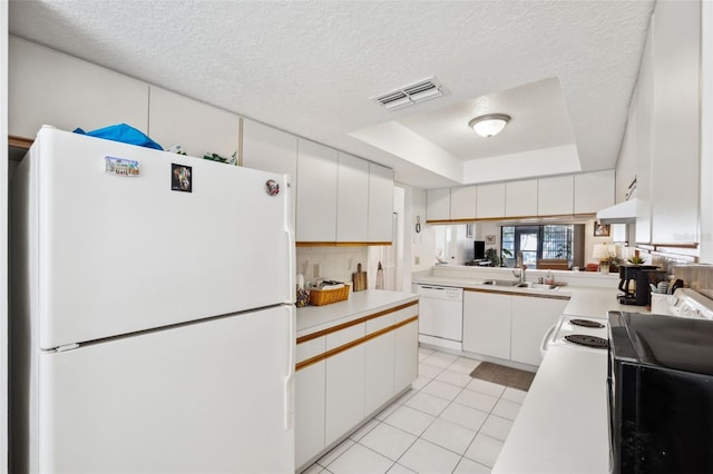 kitchen with light tile patterned floors, white appliances, white cabinets, and a raised ceiling