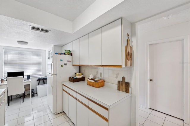 kitchen with backsplash, white cabinets, white fridge, and light tile patterned flooring