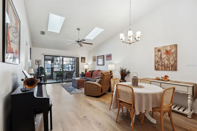 dining space featuring ceiling fan with notable chandelier, high vaulted ceiling, and light wood-type flooring