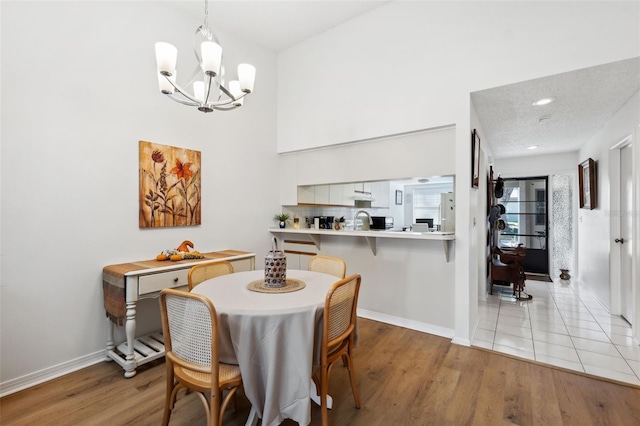 dining area with a notable chandelier, sink, and light hardwood / wood-style floors