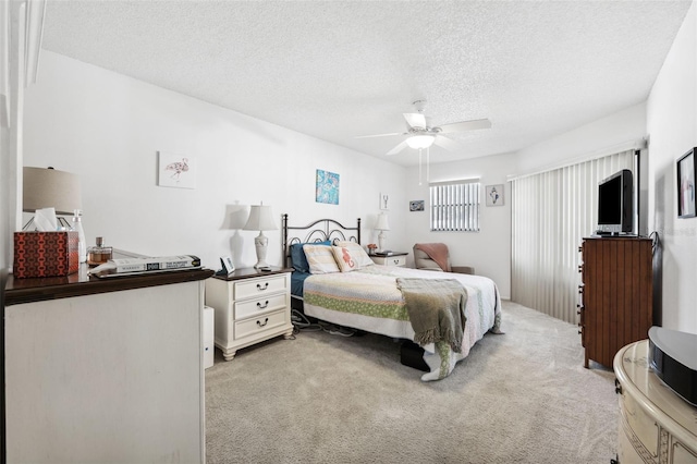 carpeted bedroom featuring ceiling fan and a textured ceiling