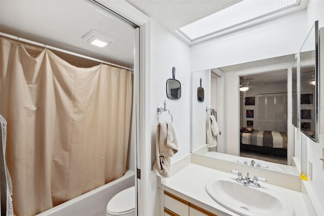 full bathroom featuring a textured ceiling, shower / bathtub combination with curtain, vanity, a skylight, and toilet