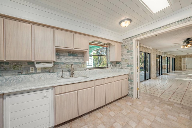 kitchen featuring decorative backsplash, light brown cabinets, light stone counters, and sink