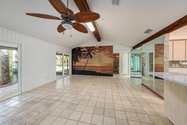 interior space featuring ceiling fan, plenty of natural light, lofted ceiling with beams, and a textured ceiling