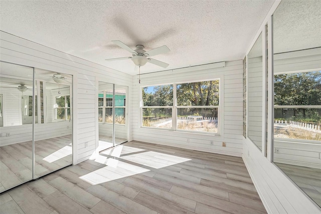 unfurnished sunroom featuring ceiling fan