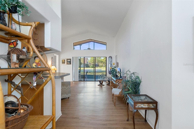 corridor with hardwood / wood-style floors and vaulted ceiling