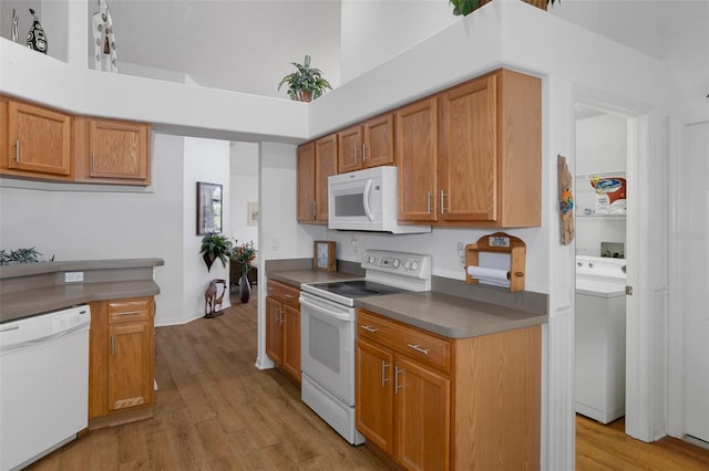 kitchen with washer / dryer, white appliances, light hardwood / wood-style flooring, and a high ceiling