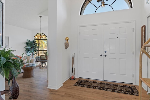 foyer featuring hardwood / wood-style floors, a towering ceiling, and a notable chandelier