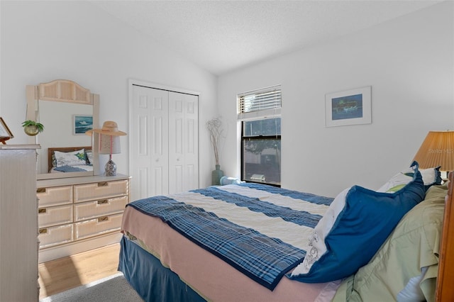 bedroom featuring a textured ceiling, a closet, carpet, and vaulted ceiling