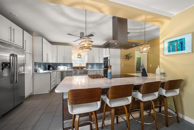 kitchen with kitchen peninsula, backsplash, stainless steel appliances, island range hood, and white cabinets