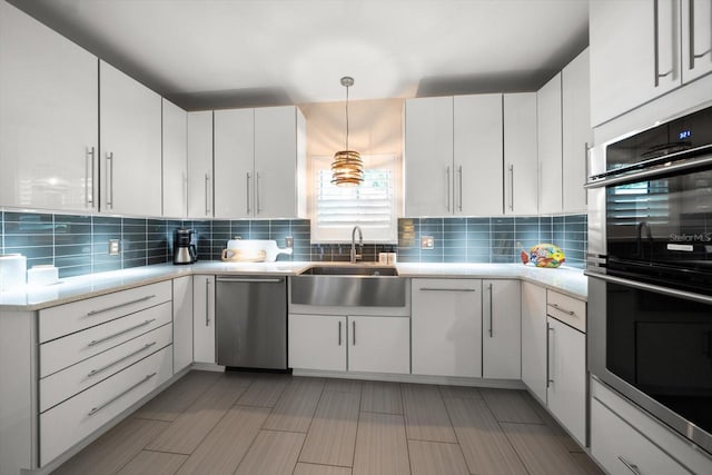 kitchen featuring white cabinets, sink, decorative backsplash, decorative light fixtures, and stainless steel appliances