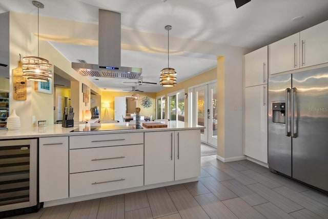 kitchen with ventilation hood, white cabinets, wine cooler, hanging light fixtures, and built in fridge