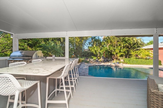 view of pool with area for grilling, exterior bar, an outdoor kitchen, and a deck