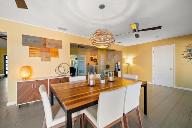 dining space with ceiling fan with notable chandelier